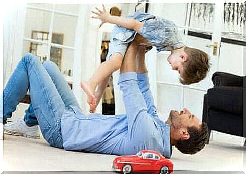 A father playing with his son with a toy car in the living room of the house.