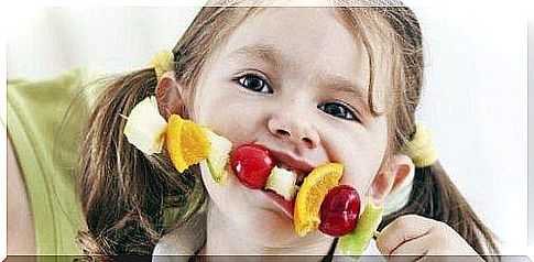 A girl eats a fruit skewer