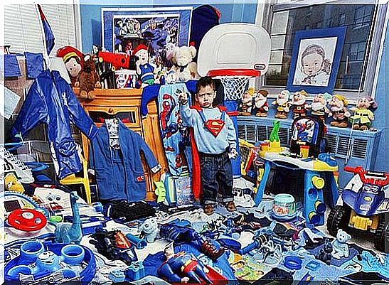 Child surrounded by lots of toys in his room, disguised as Superman