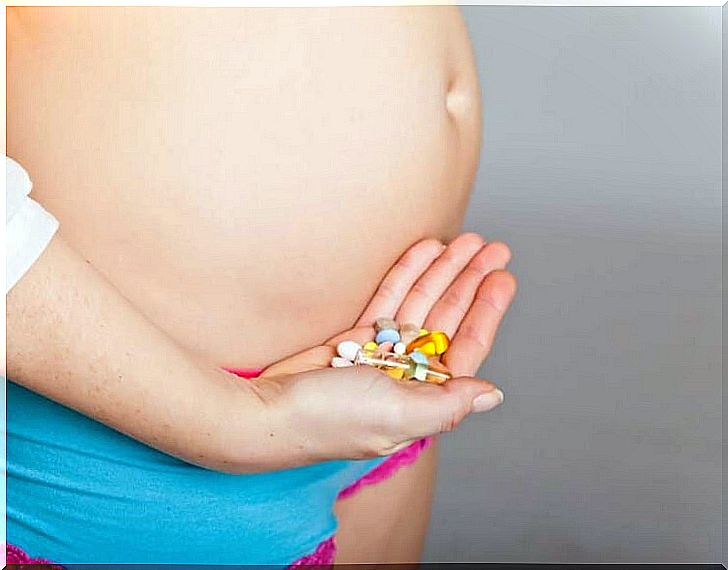 Pregnant woman with pills in hand which help provide important nutrients during pregnancy