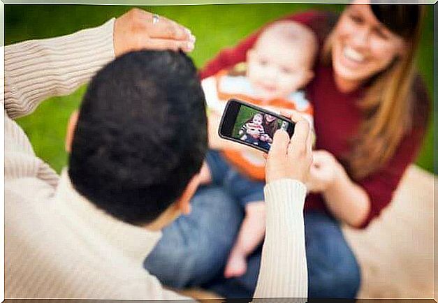 Father taking photo of his baby with camera flash which can make babies go blind