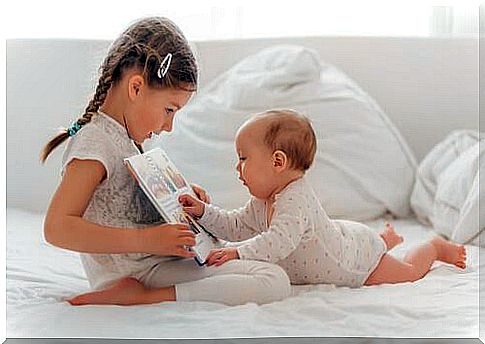 A baby listens to his sister read him a story