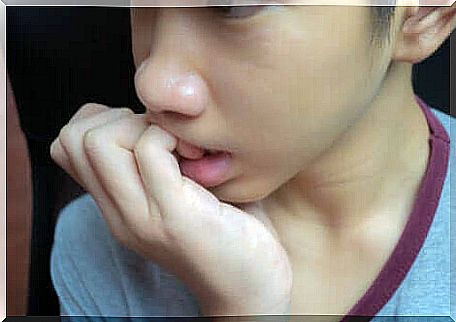 A young boy biting his nails. 