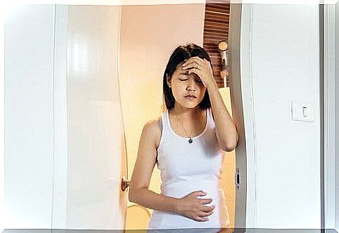 A worried pregnant woman coming out of the toilet.