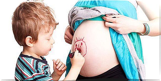 A child draws on the belly of his mother who is expecting a second child