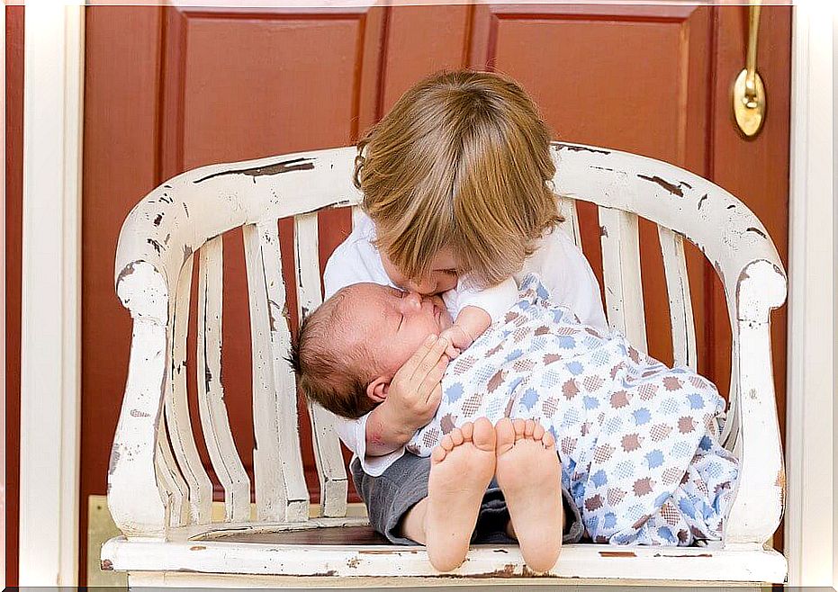 A little boy with his baby sister in his arms 