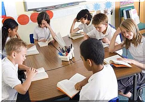 Children reading a book in a classroom.