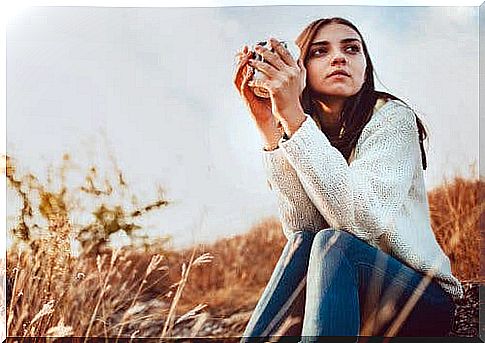 A young girl outside having a coffee.