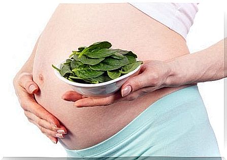 A pregnant woman with a plate of spinach