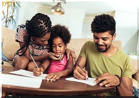 Two parents helping their young daughter with her homework. 