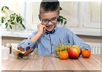 A young boy who has to choose between fruit and chocolate. 