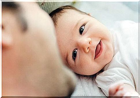 Baby smiling in front of his father, whose role is important for children 